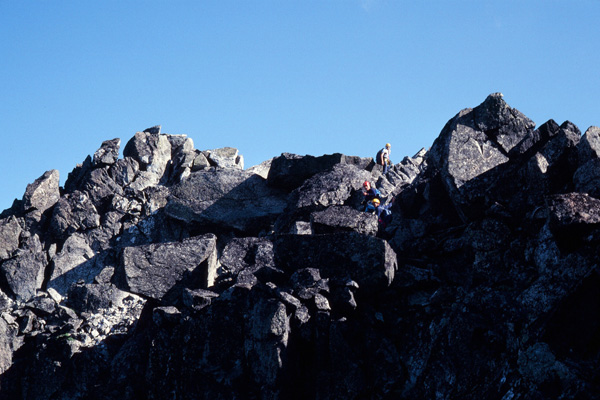 Bill, Gary, and Doug climb over large rock blocks to the summit of Sloan Peak