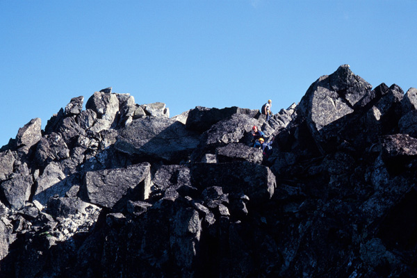 Bill, Gary, and Doug climb over large rock blocks to the summit of Sloan Peak