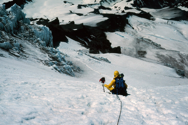 Descending around the Kautz Ice Cliffs. Linda secures herself while Ray places a picket (a snow anchor) below us. Late in the morning the softening snow can be treacherous here.