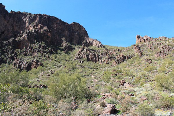 The trail passes through the rocky band to an upper saddle just out of view above