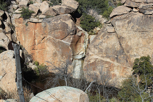 A large pool fed by a tall but narrow waterfall, likely a torrent during the monsoon