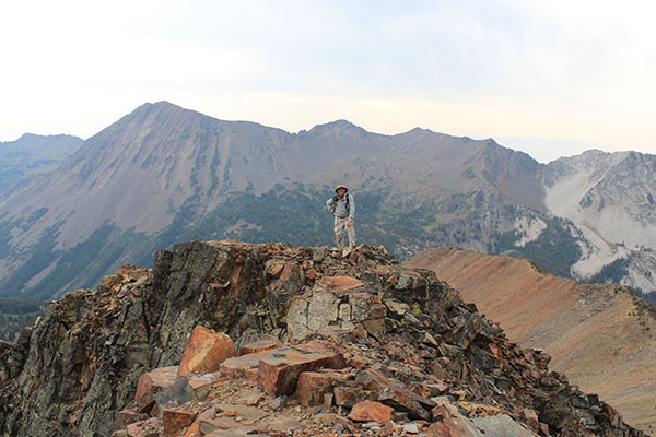 Larry pauses on the summit ridge of Krag Peak with Red Mountain behind him.
