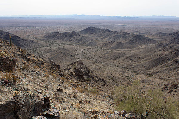 I descend from the saddle down the loose slope towards the road far below