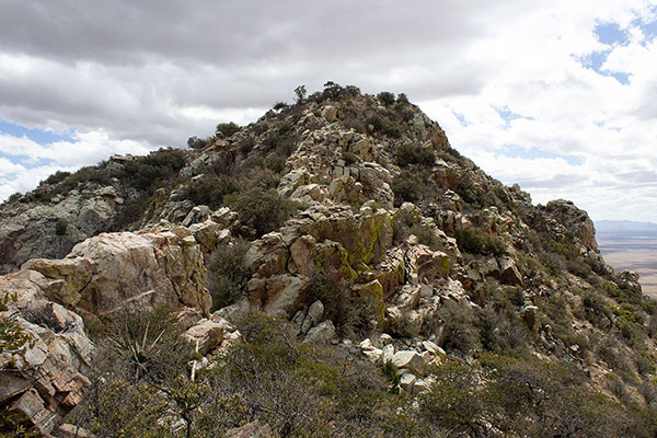 Blocks and cliffs guard the direct route to the summit; an easier route lies to the left